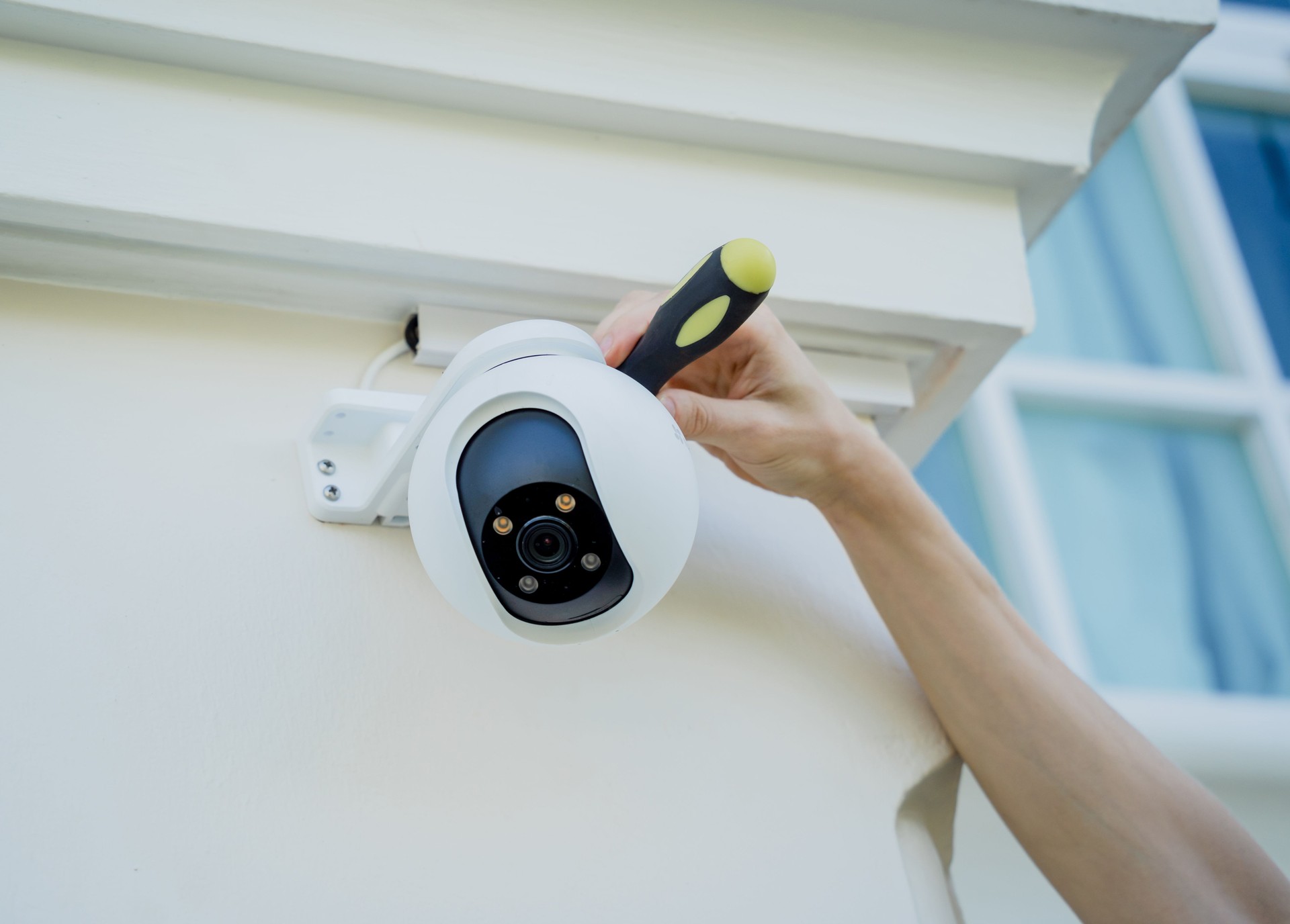 A technician installs a CCTV camera on the facade of a residential building.